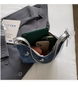 Top view of blue denim handbag interior holding a tablet, two phones, and a wallet