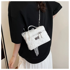 Détail du sac boîte blanc matelassé avec chaîne en perles et nœud en dentelle