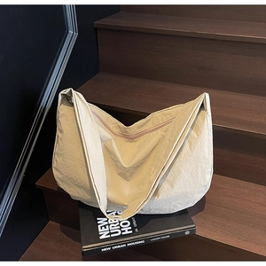 Détail du sac bandoulière en nylon beige avec texture plissée sur fond en bois moderne
