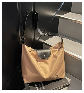 Detail of khaki oxford tote bag featuring black leather flap and metallic buckle clasp