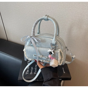 Close-up of light blue bowling bag with lace bow pocket and pearl chain detail