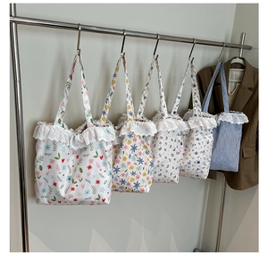Detail showing various floral canvas tote bags with delicate lace trim on a rack
