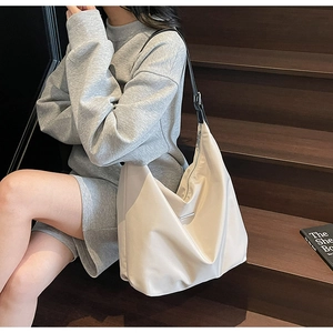 Detail of a minimalist cream shoulder bag with adjustable black strap and silver logo