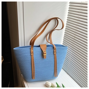 Dettaglio della trama del sacco tote blu intrecciato con nappe in pelle marrone e fibbia