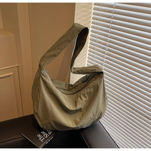 Vue détaillée du sac croissant en nylon vert olive montrant la texture et la bandoulière