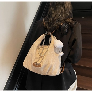 Détail du sac jacquard beige avec chaîne en perles, logo et breloque nuage en peluche