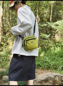 Vista esterna di una borsa a tracolla in nylon verde senape con tessuto impermeabile e logo