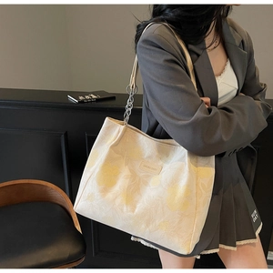 Detail of floral jacquard tote bag featuring leather logo tag and silver chain strap