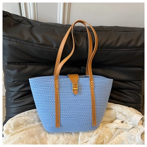 Dettaglio della borsa tote blu intrecciata con fibbia in pelle marrone e trama di cotone