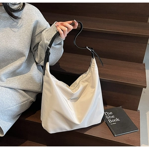 Detail of adjustable black leather strap and silver metal buckle on cream tote bag