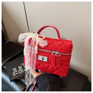 Détail du sac boîte rouge matelassé avec nœud en dentelle blanche et perles élégantes