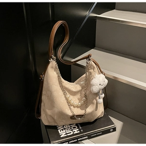 Détail du sac cabas beige avec garniture marron, chaîne en perles et pendentif en peluche