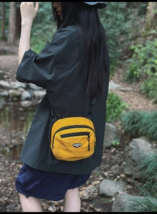 Dettaglio borsa a tracolla gialla in nylon con patch logo e cerniere nere
