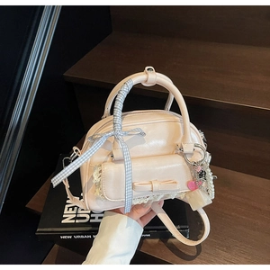 Detail of light pink bowling bag with bow, lace pocket and blue plaid ribbon on the handle
