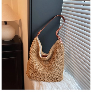 Close-up of handmade woven straw bucket bag with brown leather strap and mesh texture
