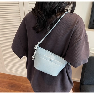 Détail d'un sac bandoulière bleu clair à texture grainée et pendentif ours
