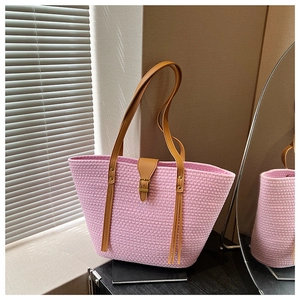 Dettaglio borsa tote rosa tessuta a mano con cinturini in pelle marrone e fibbie in metallo