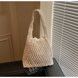 Close-up of a white woven bucket bag featuring a hollow mesh design and inner drawstring pouch