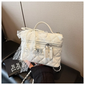Détail du sac boîte matelassé blanc avec nœud en dentelle, perles et chaîne en métal
