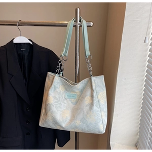 Detail of light green floral tote bag with silver chain straps and brand patch