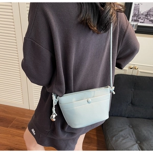 Détail du sac bandoulière bleu clair texture litchi avec pendentif lune argenté