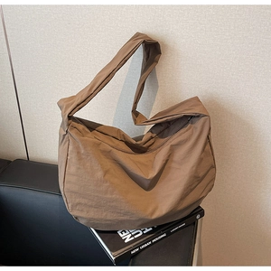 Détail d'un sac bandoulière en nylon marron montrant la texture plissée du tissu