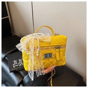 Détail du sac boîte jaune matelassé avec perles blanches et nœud en dentelle
