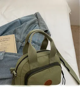 Detaillierte Draufsicht einer grünen Nylon-Quadrat-Handtasche mit Umhängegurt auf Weiß