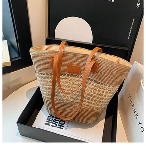 Dettaglio borsa tote in paglia intrecciata kaki con manici in pelle in scatola regalo