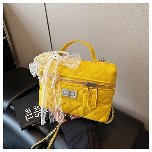 Détail du sac matelassé jaune avec un nœud en dentelle de perles et bandoulière chaîne