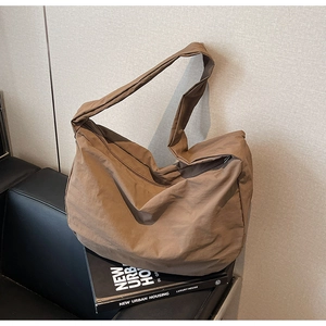 Gros plan du sac cabas en nylon marron café avec texture plissée contre un mur