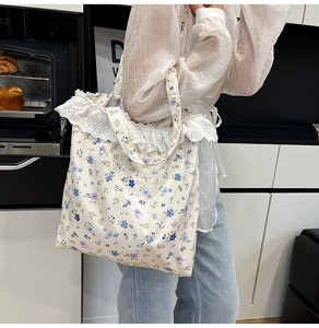Detailed shot of floral canvas tote bag with delicate white lace trim and blue flower patterns