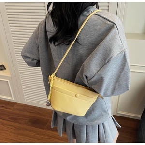 Détail de la texture en cuir jaune vif et du charme métallique sur le sac bandoulière chic
