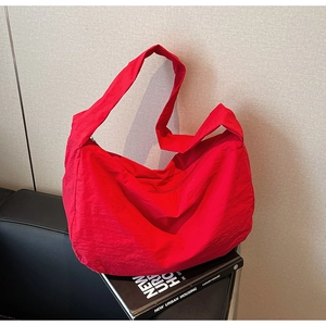 Gros plan détaillé d'un grand sac bandoulière rouge en nylon sur un livre noir