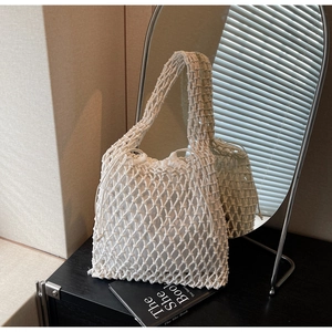 Detail of white woven bucket bag with drawstring liner and textured knit handles