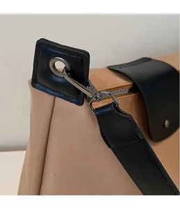 Close-up of gun-metal swivel hook and black leather D-ring on khaki nylon tote bag