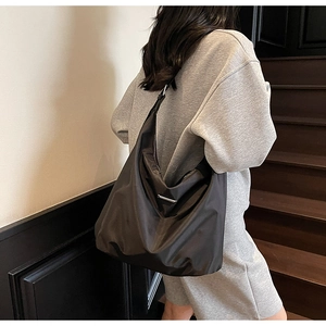 Detail showing the adjustable strap and silver metal buckle on a black nylon crossbody bag