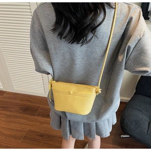 Détail d'un sac seau jaune en cuir grainé avec bandoulière porté par un mannequin