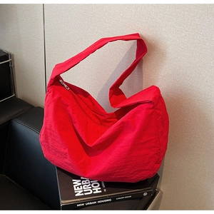 Gros plan d'un sac bandoulière en nylon rouge avec large sangle sur cuir