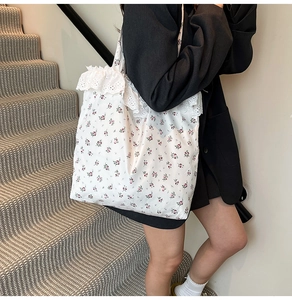 Close-up of white floral canvas tote bag with delicate lace trim and ruffle details