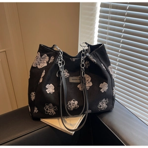 Close-up of black floral tote bag with silver chain handle and SAKURA DUA leather patch