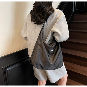 Detail of dark gray large nylon hobo bag with sleek metal logo and adjustable strap