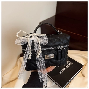 Détail du mini sac matelassé noir avec nœud en perles et élégant ruban en dentelle