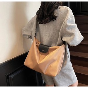 Detail of light brown nylon tote with black leather flap and silver snap button