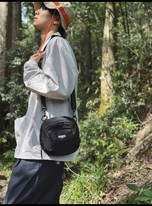 Borsa a tracolla in nylon nero con cerniera anteriore e logo Shilaien in ambiente esterno