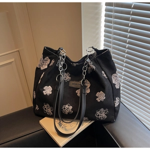 Close-up of black canvas tote bag with white floral pattern and dual leather chain straps