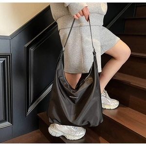 Detail of a large black nylon hobo bag with silver metallic zipper and adjustable strap