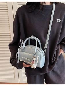 Pale blue bowling handbag with lace trim and bow charm shown in a crossbody style