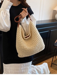 Handwoven beige straw bucket bag with brown leather handles for seaside beach vacation