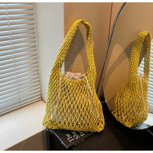 Detailed macro view of yellow hand-woven bucket bag with a beige drawstring inner liner pouch